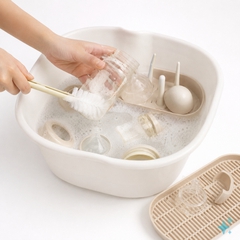 hình ảnh bàn tay đang rửa bình sữa cho bé, nền trắng, thêm cả chậu rửa bình sữa cho bé ....